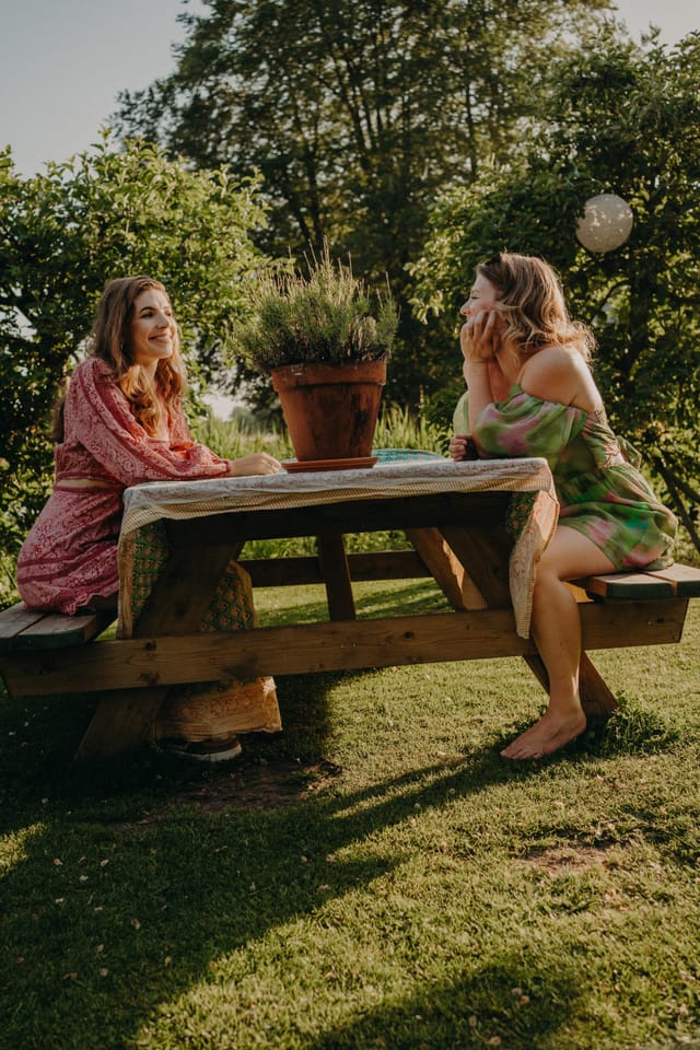 Twee vrouwen lachen samen aan een picknicktafel buiten